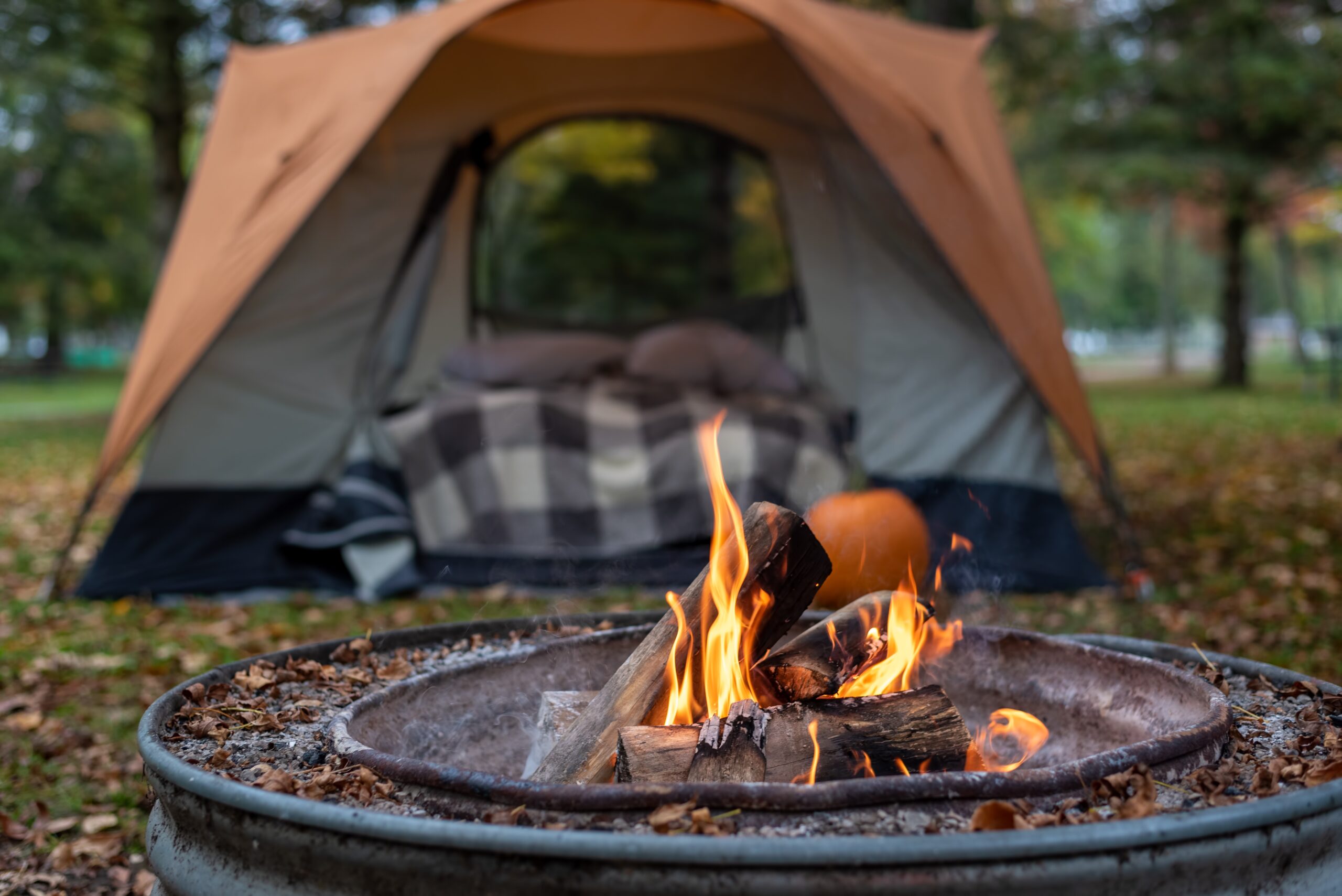 Burning campfire with cozy tent in background