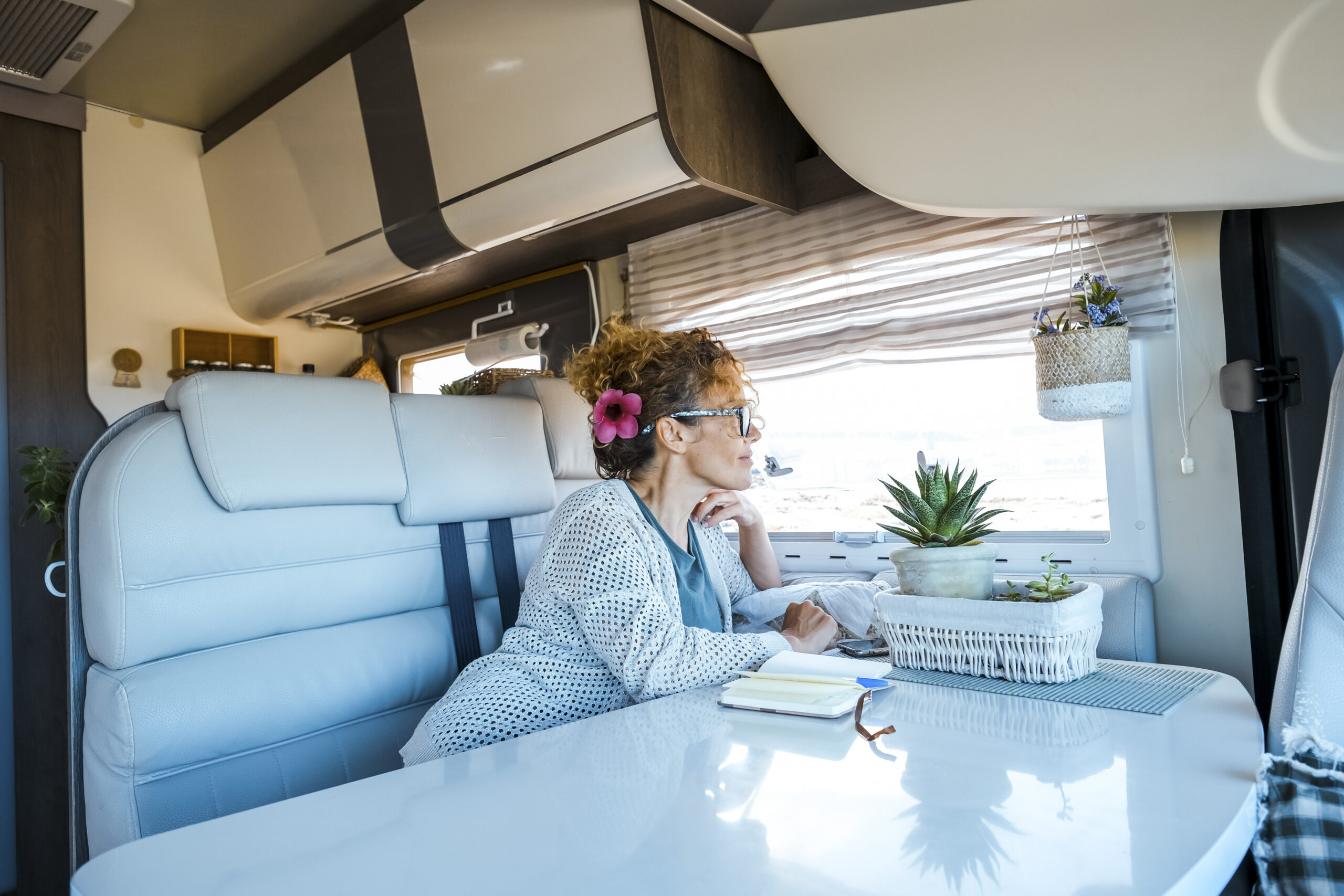 One woman relaxes inside a camper van motorhome rv vehicle. lady loves to relax sitting on the sofa looking outside. Freedom travel concept. Spring weekend traveler female lifestyle. Independence