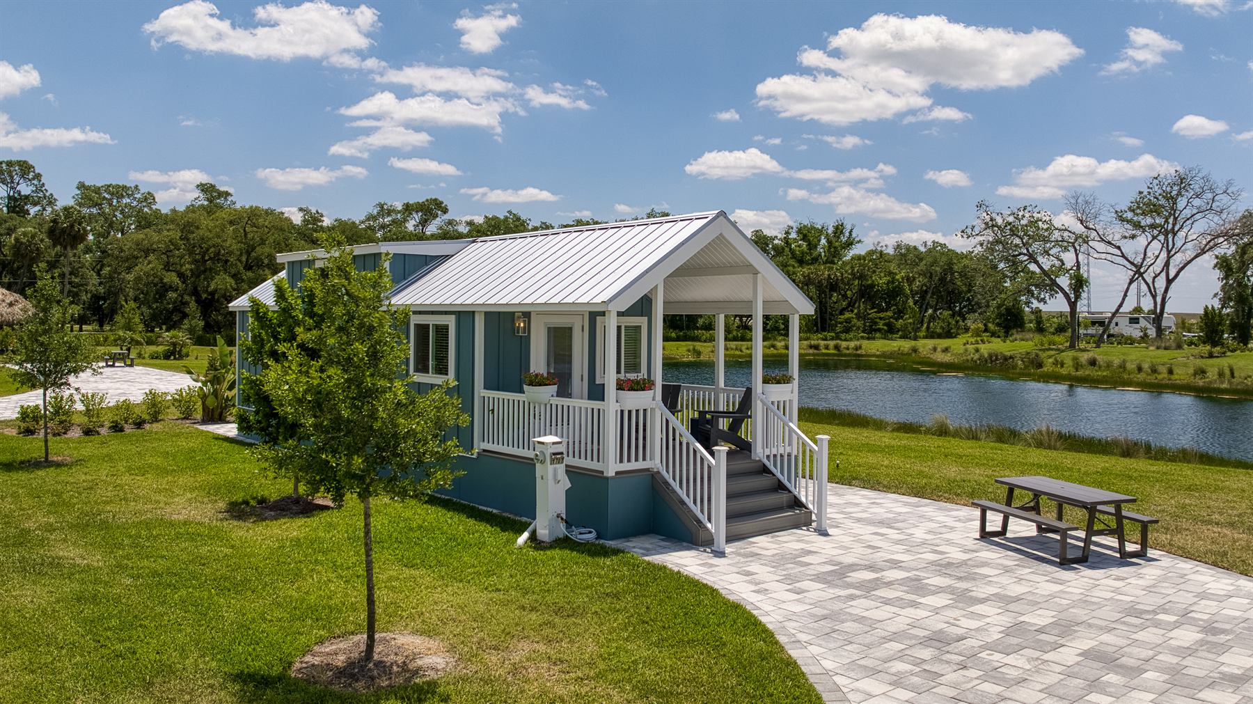 Blue Park Model with porch beside a lake at Olde Florida Motorcoach and RV Resort