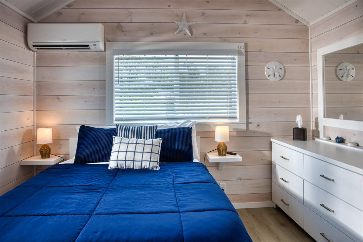 Park model bedroom with blue bedding and white dresser